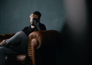 Man sitting on couching holding head from headache