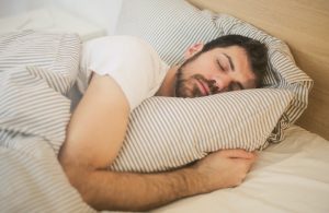 Man sleeping in bed with striped sheets