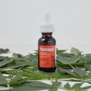 Tanasi CBD tincture with white background and hemp leaves