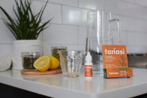 Tanasi CBD water soluble with glass and lemon on kitchen countertop