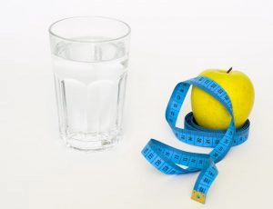 Glass of water and apple with measuring tape