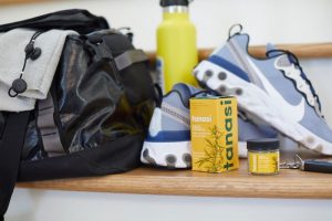 Tanasi CBD salve with shoes, gym bag, and water bottle