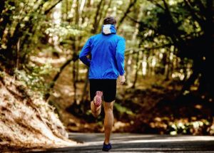 Man in blue jacket running through nature