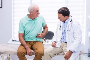 Senior man showing a doctor his ulcer pain