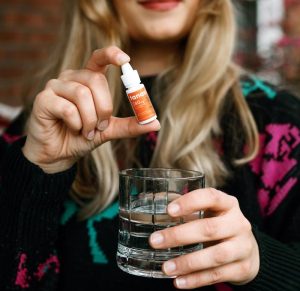 woman holding cbd water soluble and glass of water