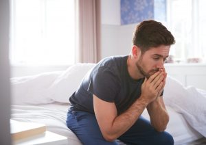 fatigued man sitting on bed