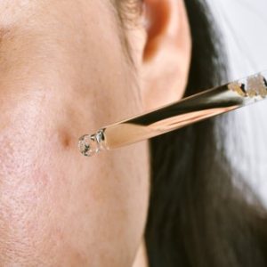 woman applying face serum to skin