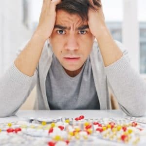 Can CBD Help with Anxiety? - anxious man surrounded by pills