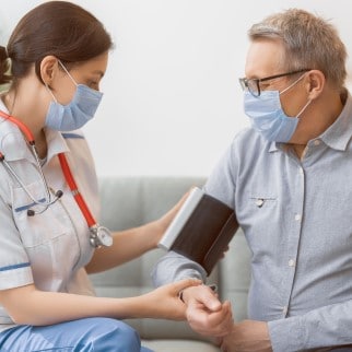 CBD And Blood Pressure - nurse measuring the patient's blood pressure both wearing a face mask